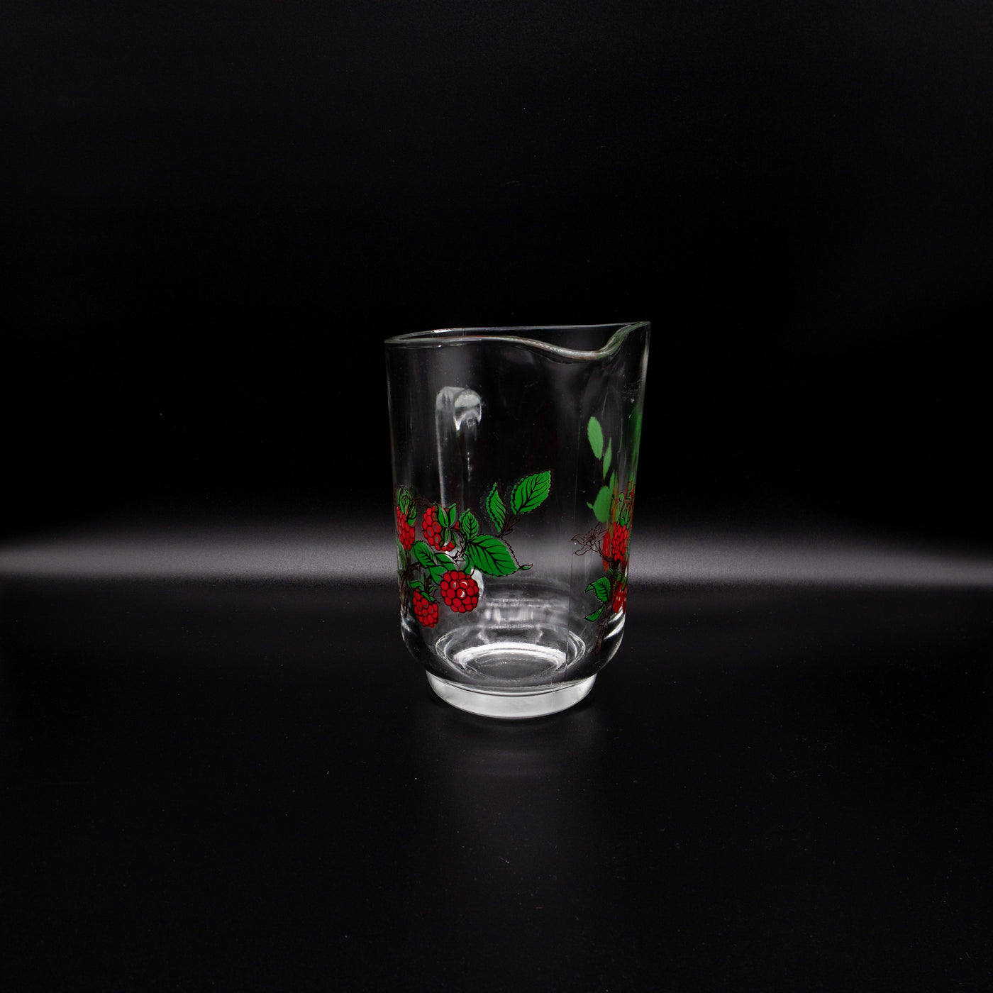Saftkrug mit Himbeeren, leicht schräg stehend